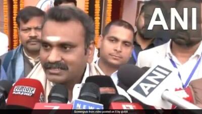 Dr. L. Murugan speaks to reporters holding microphones from several news organisations